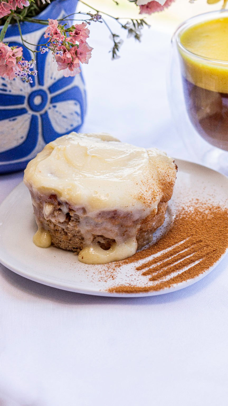 Cinnamon Roll de 185 g con cobertura cremosa, servido en un plato